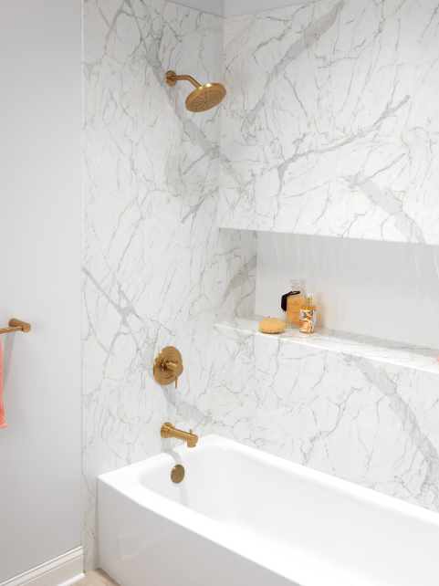 White bathtub with marble walls and gold fixtures